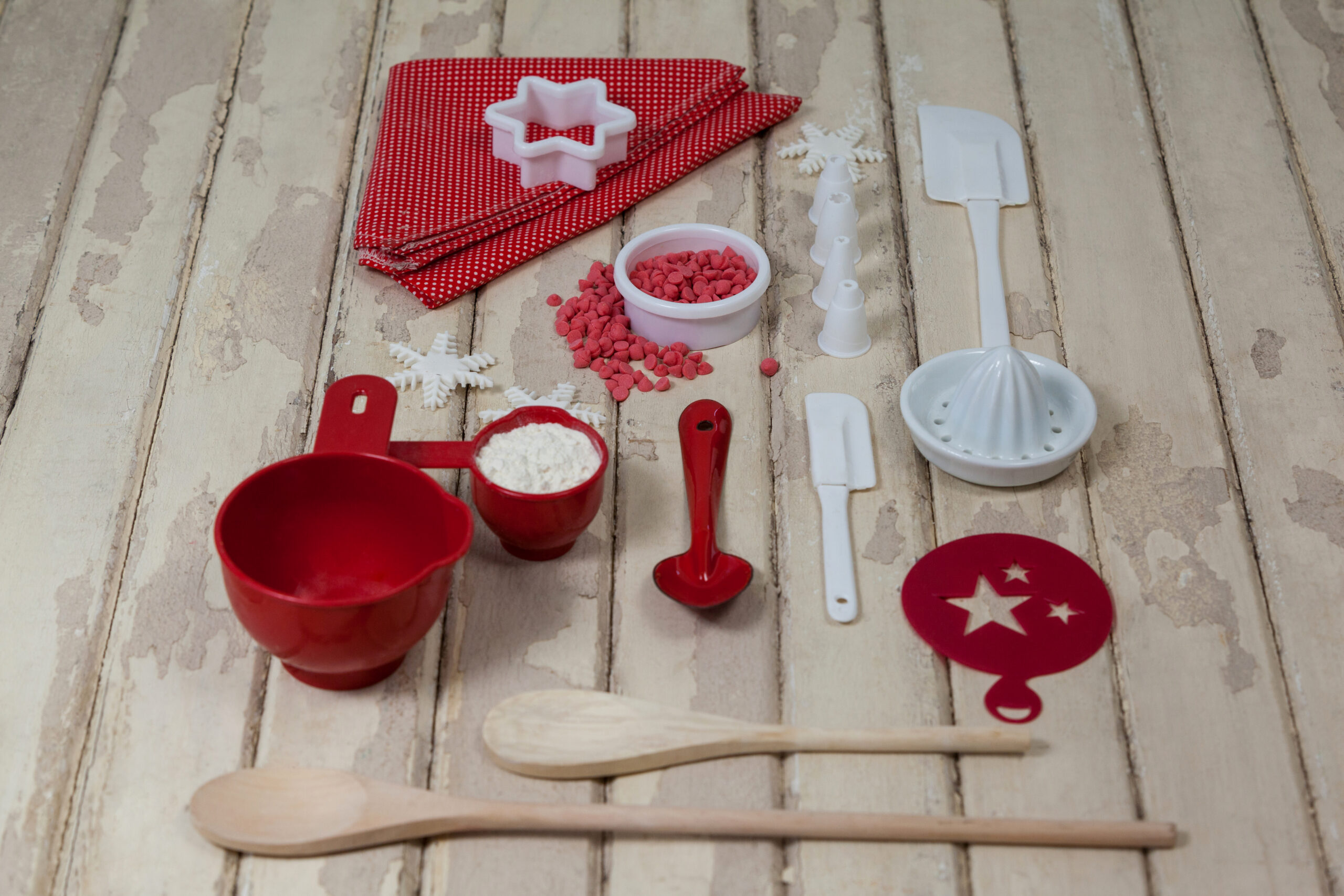 Spatula, spoons, icing sugar, dessert toppings and cookie cutter on wooden board